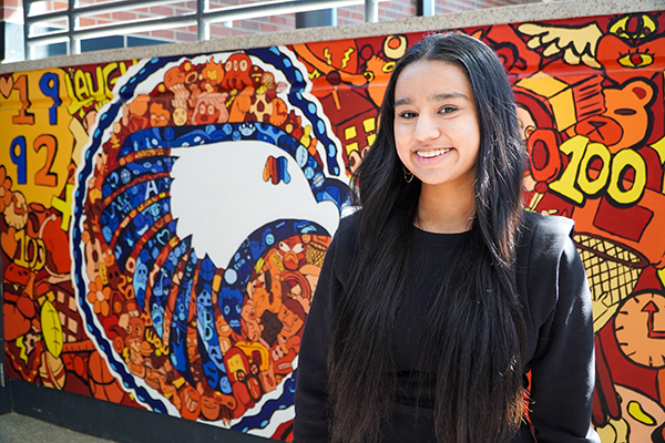 Komal Kaur stands in front of beautiful mural