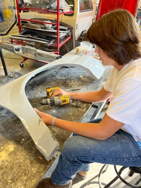 Noah repairing and priming car fender
