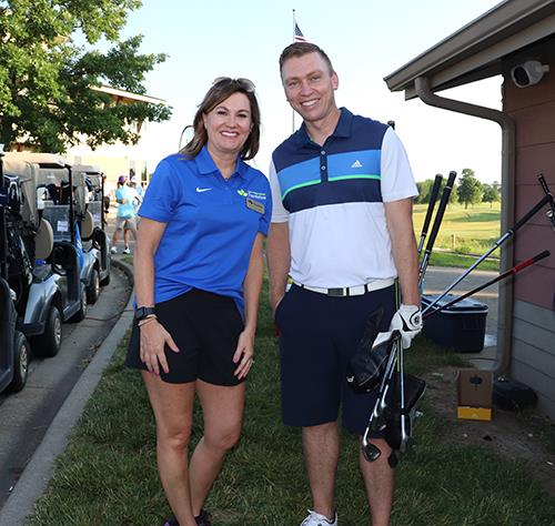 photo of woman and man holding golf clubs