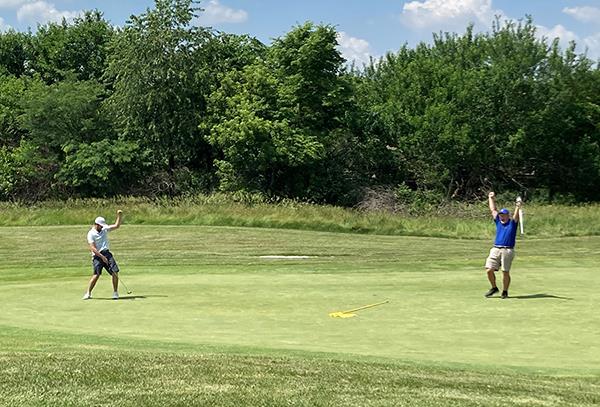 photo of two golfers cheering on green