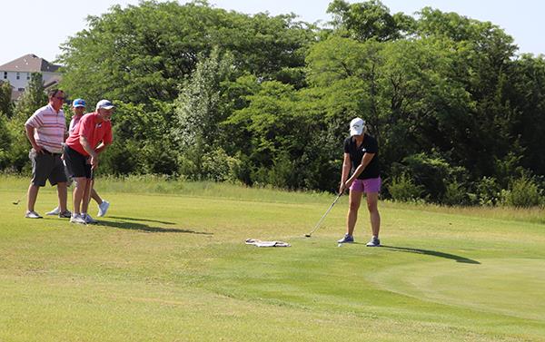 photo of three golfers helping to line up a put