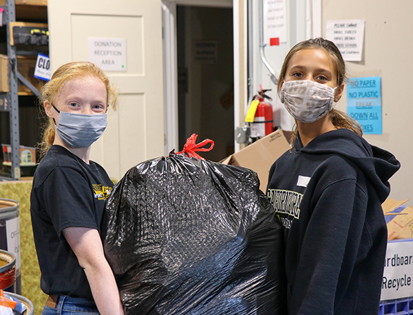 photo of girls carrying bag of clothing