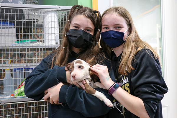 photo of two girls holding a puppy