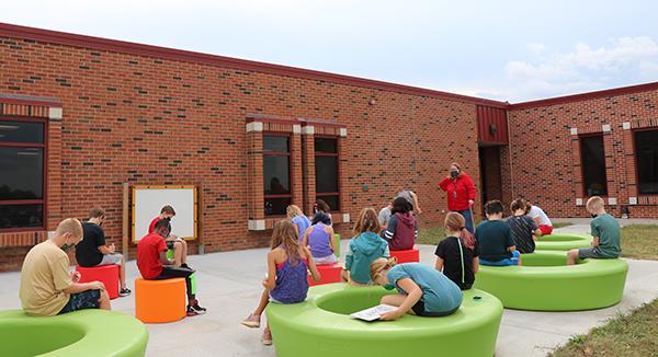 photo of students sitting on brightly colored outdoor benches