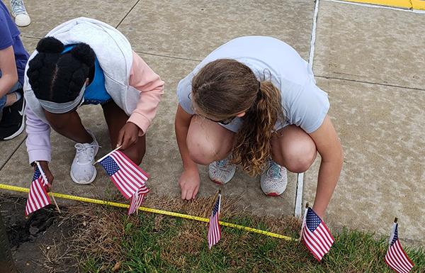 students plant flags by sidewalk