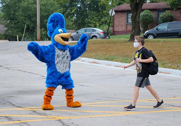 school mascot escorts boy in crosswalk