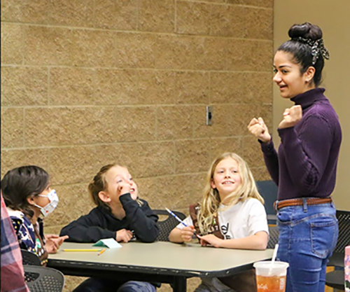 Mahi talks with students seated at a table