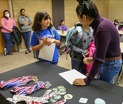 Mahi Kohli talks with student at sign-in table