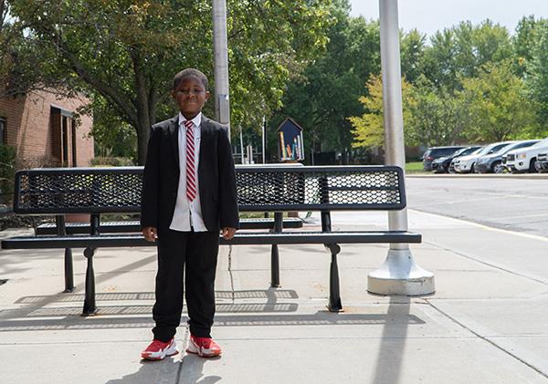 Sekou stands in front of his school