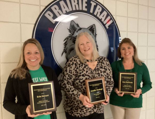 three women holding plaques