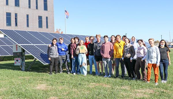 group of students pose by solar panels
