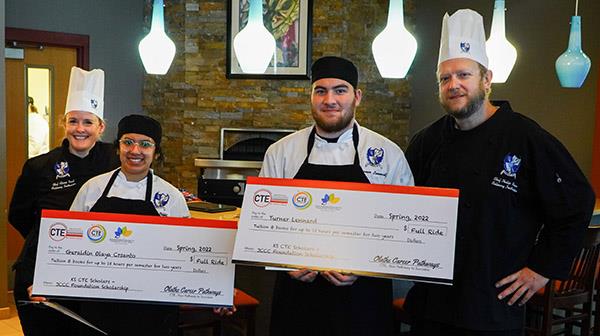two culinary students hold their mock checks