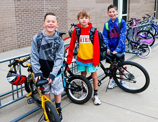 three boys stand by their bikes