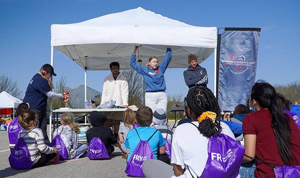 high school student speaks to elementary age students