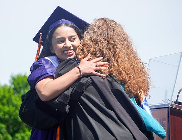girl and principal hug on stage