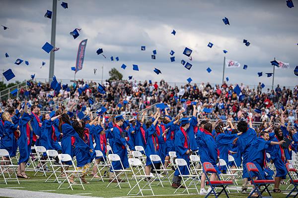 graduates throw their caps up
