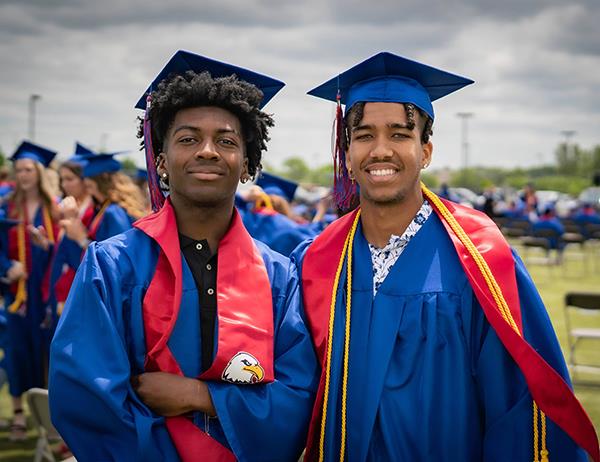 two male graduates smile for the camera