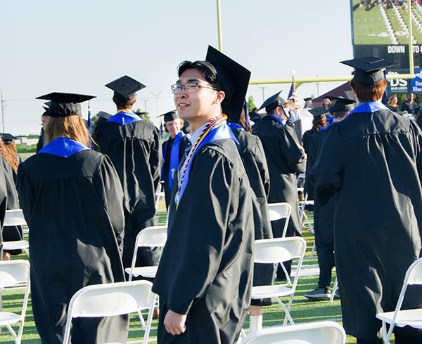 male graduate looks toward the stadium stands