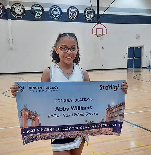 cheerleader holds award banner while standing in gymnasium