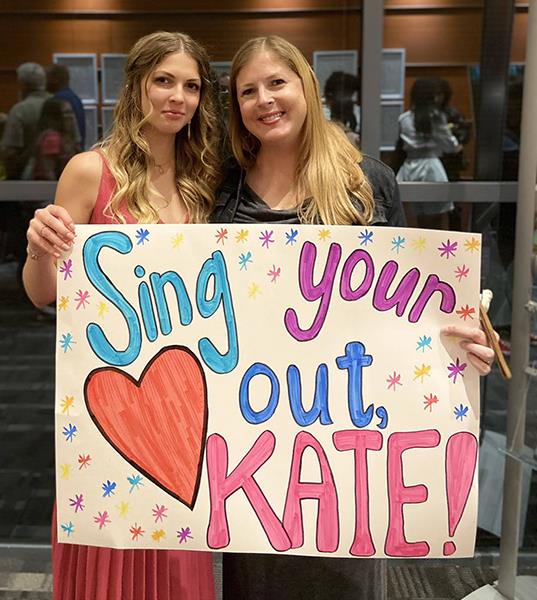 Kate holds a sign that says \
