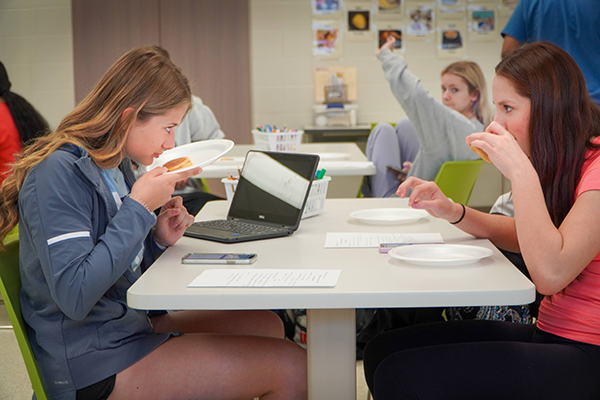 two girls sniff pancakes before eating and rating them