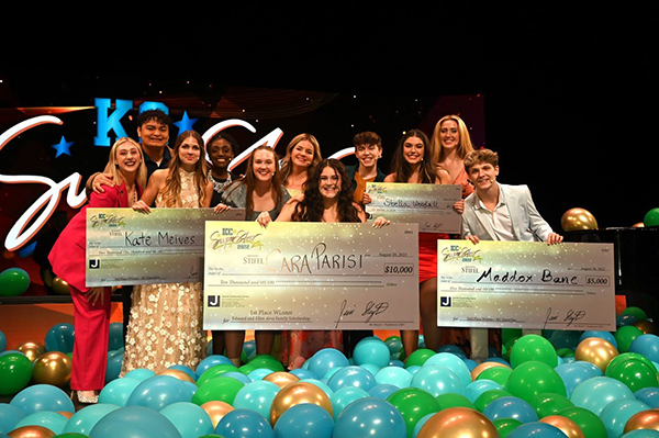 group of high school students holding large fake checks