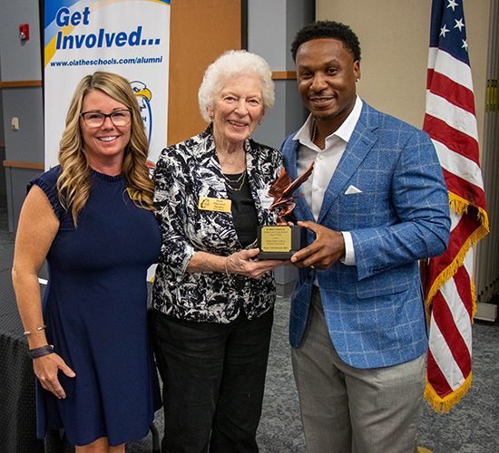 two women present award statuette to man
