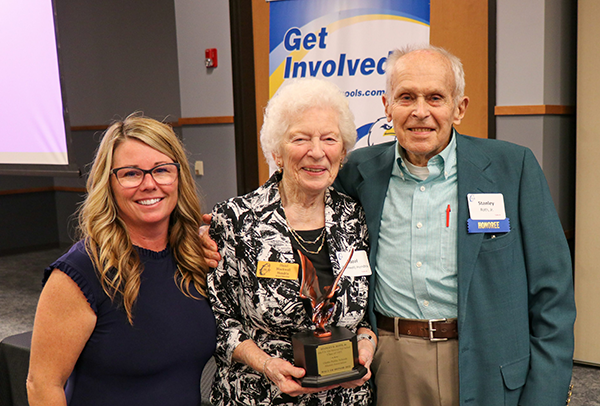 two women present award statuette to man