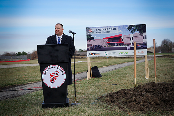 Brent Yeager at podium, with new school sign behind him