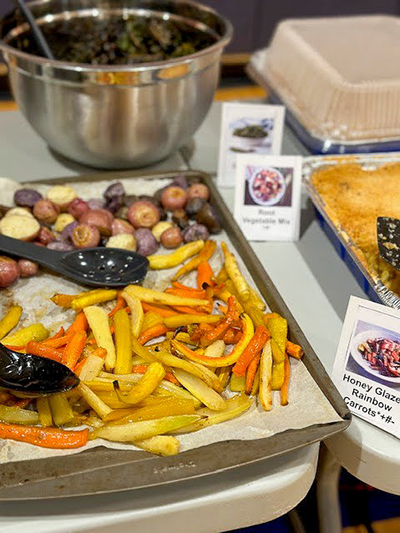 display of cooked carrots, potatoes and kale