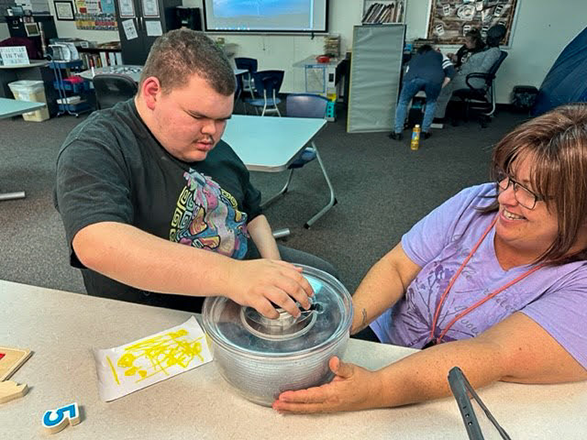 student washes kale with teacher's help