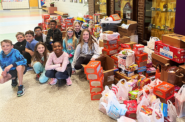 students pose by boxes of donated food