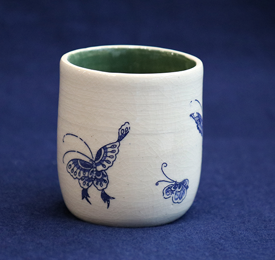 white stoneware cup with blue butterflies painted on it