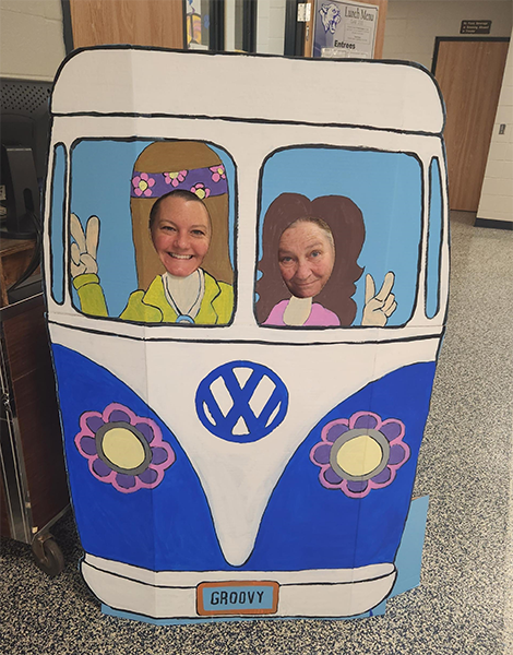 people poke their heads through holes in a cardboard VW van