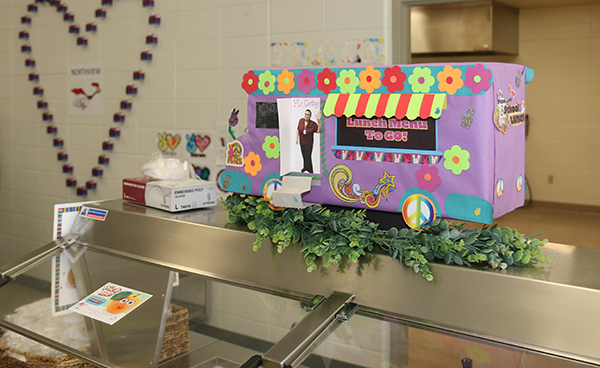 decorated cardboard van sits atop salad bar