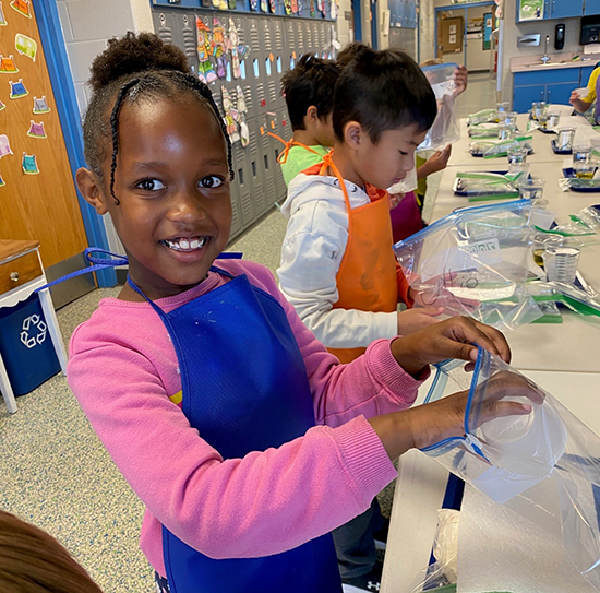 first grader dumps ingredients into a plastic bag