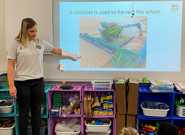 adult points to harvesting machinery on presentation screen
