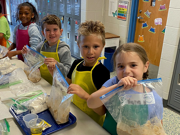students hold bags of pizza dough