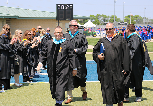 district leaders in graduation gowns lead processional
