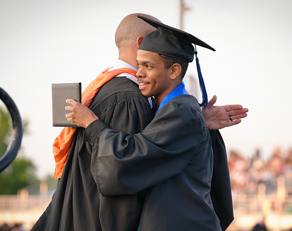 administrator and student hug on stage