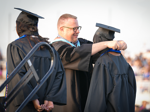 superintendent places medal around the neck of a graduating senior