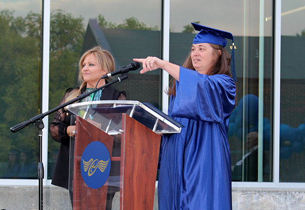 woman at podium points to son in audience