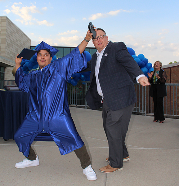graduate and superintendent do a little pose