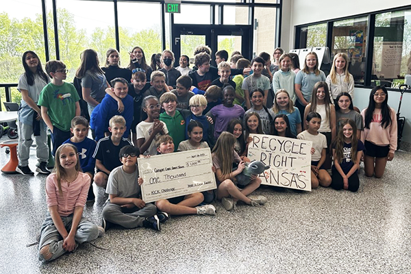 students hold mock check and poster for their project