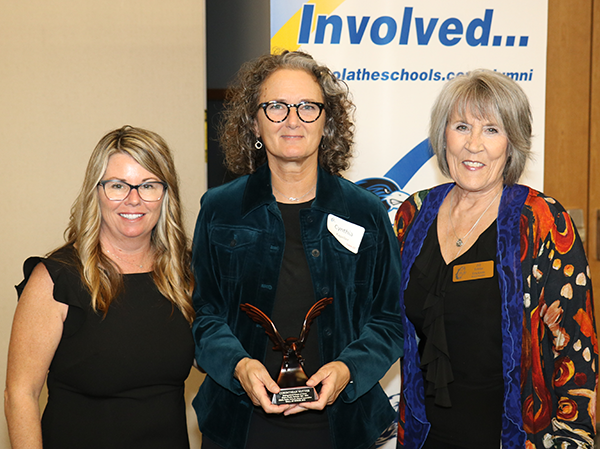 three women pose for camera with award
