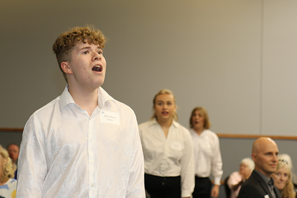 students singing amid tables of diners