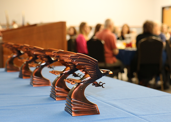 Wall of Honor statuettes on a table with audience in the background