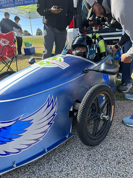 driver in electric race car, wearing helmet
