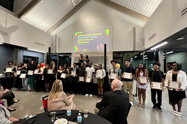 students stand in a line holding award certificates