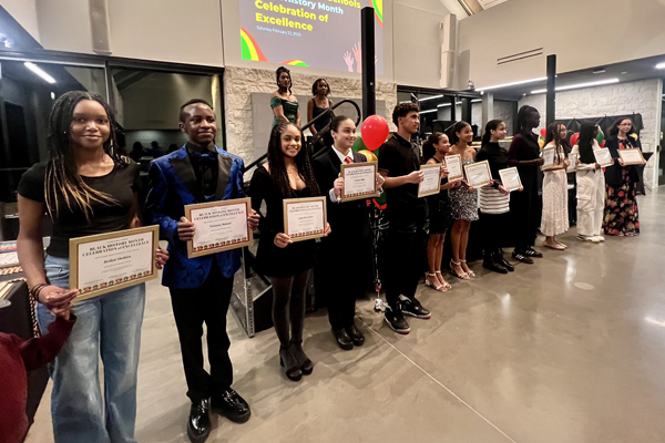 students stand in a line holding their award certificates